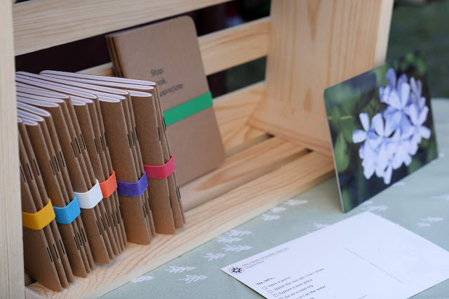 Happier Place sustainable notebooks (recycled, plant-based ink, B-Corp-made), multiple-choice postcards, and metal prints.