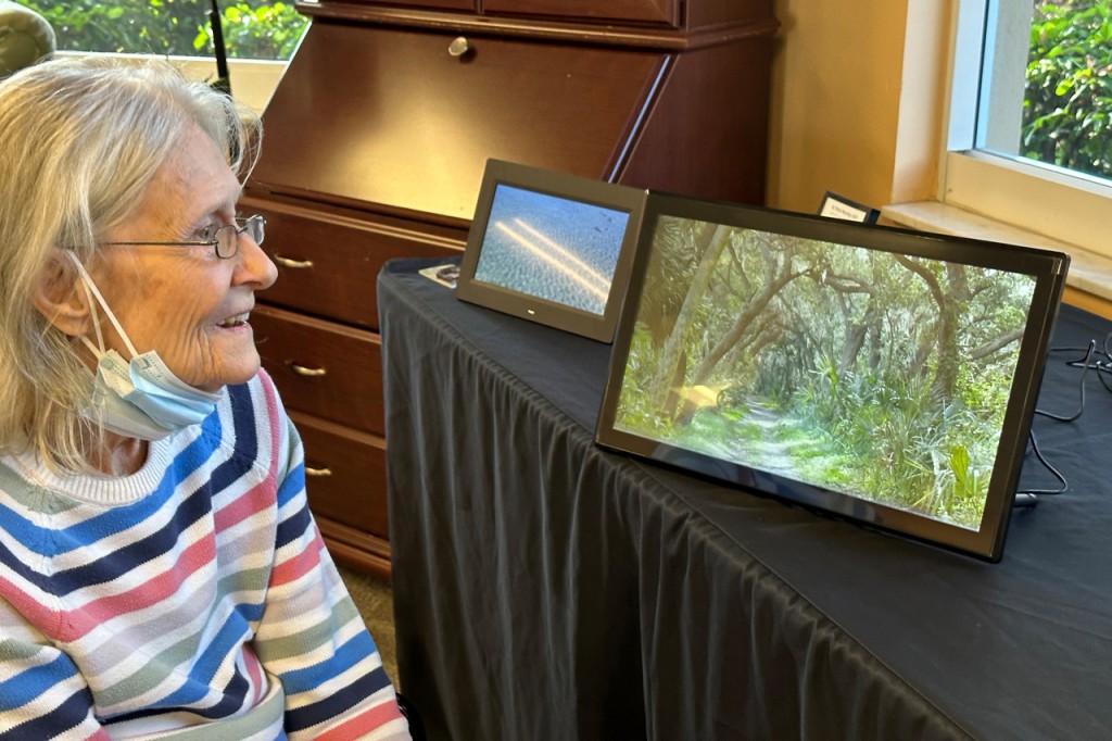 Smiling woman, digital screen of wooded trail, St. Pete Moving Still