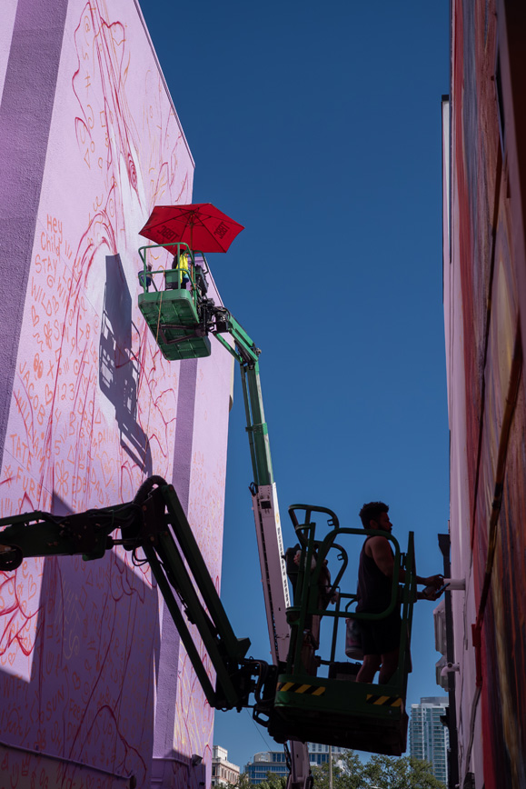 Two muralists on lifts, Dreamweaver and Isaac